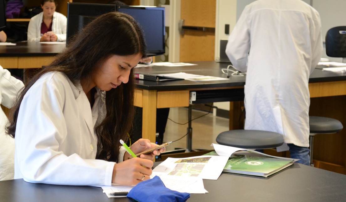 woman in lab coat taking notes