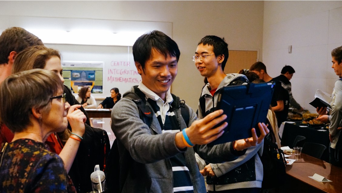 Man looking at a tablet with people around him