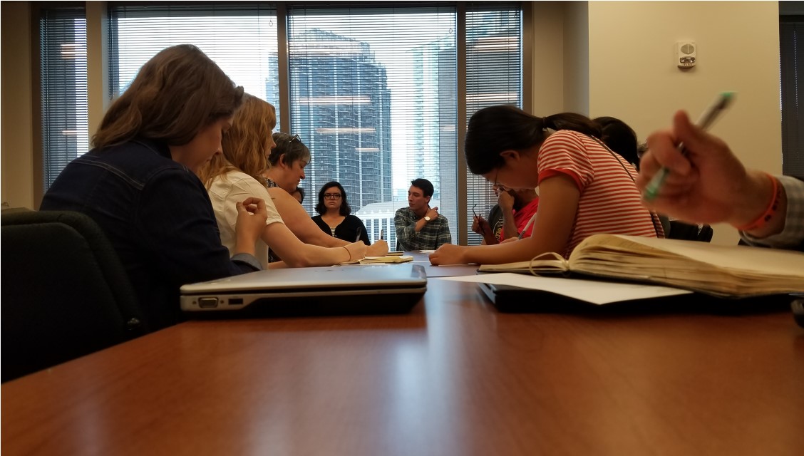 People sitting at a desk writing in notebooks